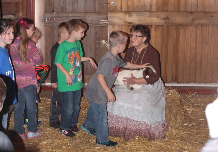 Students petting baby goat during Spring on the Farm HATS class
